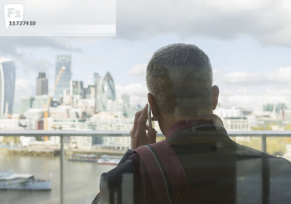 Geschäftsmann im Gespräch am Handy auf dem Stadtbalkon mit Blick auf die Stadt  London  UK