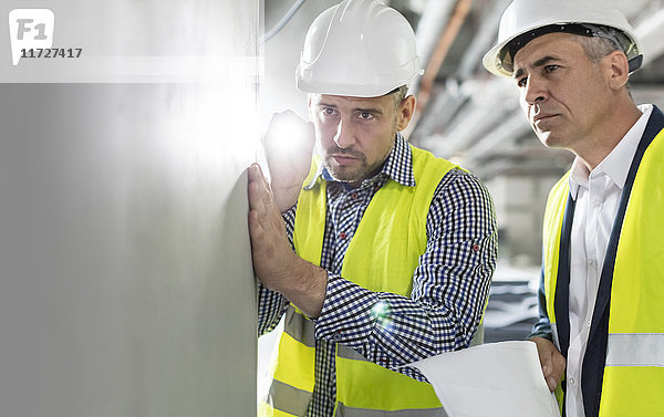 Ingenieur mit Taschenlampe zur Untersuchung der unterirdischen Wand auf der Baustelle