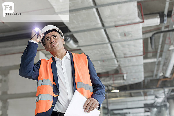 Vorarbeiter mit Taschenlampe beim Bauarbeiter
