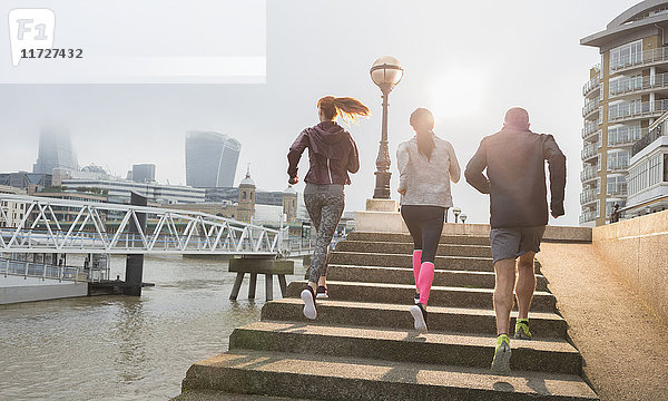 Läuferinnen und Läufer  die die sonnige  städtische Uferpromenade hinauflaufen.