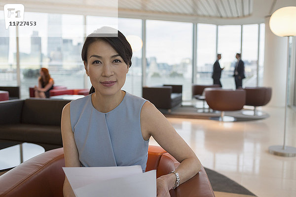 Porträt einer selbstbewussten Geschäftsfrau  die den Papierkram in der Bürolounge bespricht