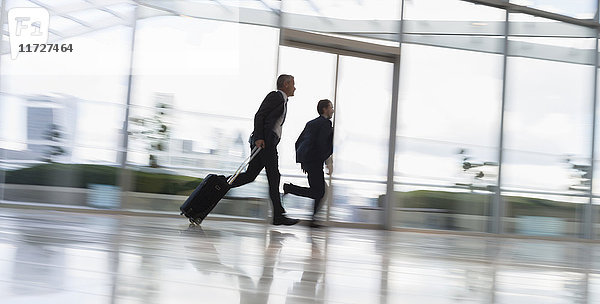 Geschäftsleute  die mit dem Koffer rennen  in den Flughafen hetzen.