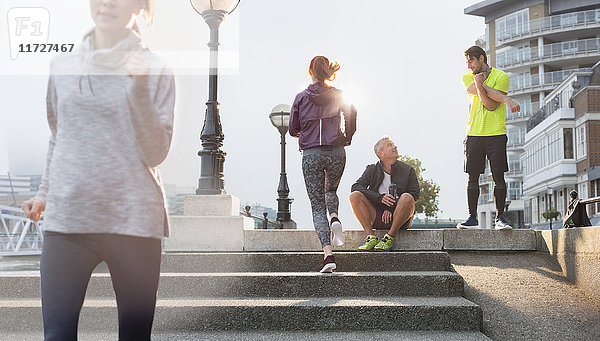 Läuferinnen und Läufer ruhen  strecken und laufen auf sonnigen Stadttreppen