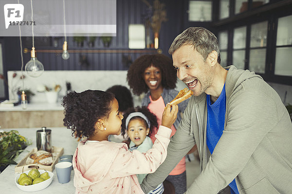 Multiethnische Tochter füttert Toast an Vater in der Küche