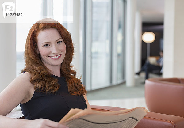 Portrait lächelnde Geschäftsfrau mit roten Haaren in der Bürolounge