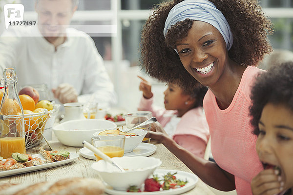 Portrait lächelnde Mutter beim Frühstücken mit junger Familie am Tisch