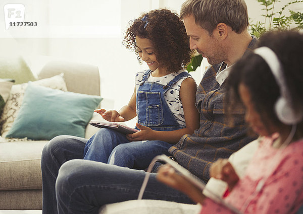 Multi-ethnischer Vater und Tochter mit digitalem Tablett auf Sofa