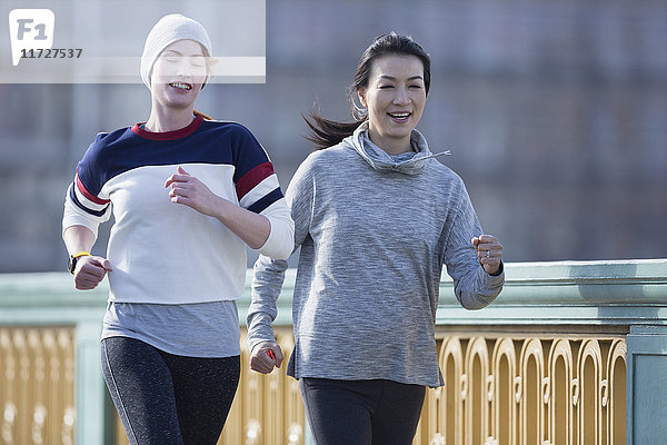 Lächelnde Läuferinnen laufen am Geländer entlang