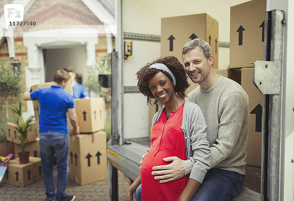 Portrait lächelndes schwangeres Paar beim Umzug vor dem neuen Haus