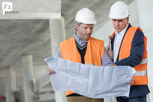 Männliche Ingenieure untersuchen unterirdische Baupläne auf der Baustelle