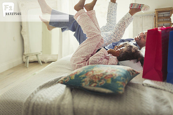 Vater und Töchter im Pyjama treten die Beine auf das Bett.