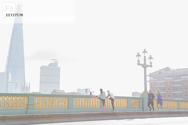 Läufer beim Laufen und Strecken auf der sonnigen  nebligen Stadtbrücke  London  UK