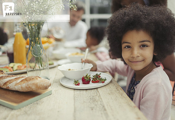 Portrait lächelndes Mädchen beim Essen von Erdbeeren am Frühstückstisch