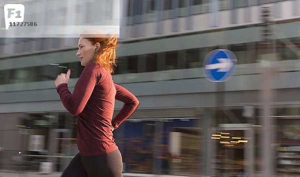 Läuferin  die an einem städtischen Gebäude entlang läuft.