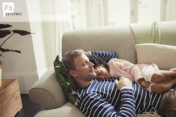 Zärtlicher  gelassener  multiethnischer Vater und Tochter beim Schlafen auf dem Sofa.