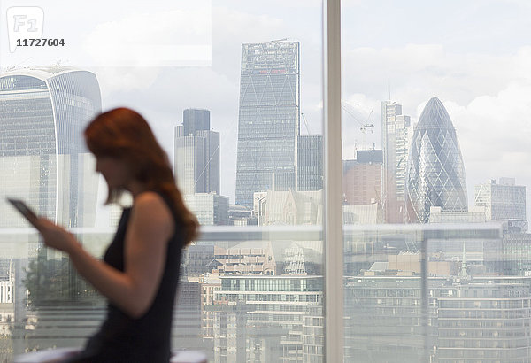 Geschäftsfrau mit digitalem Tablett am Stadtfenster mit Stadtansicht  London  UK