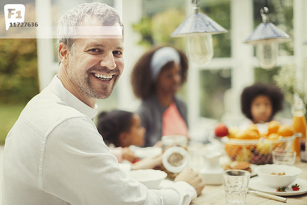 Portrait begeisterter Vater mit Familie am Frühstückstisch