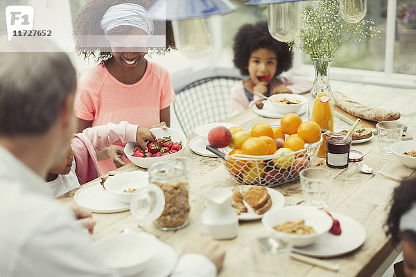 Multi-ethnische junge Familie beim Frühstücken am Tisch