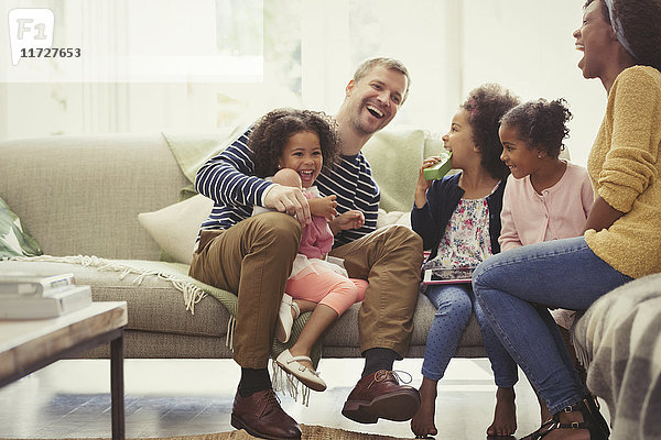 Multi-ethnische junge Familie lacht auf dem Sofa