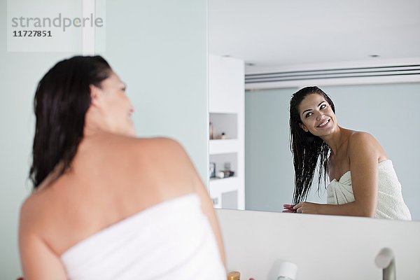 Brünette Frau bürstet ihr Haar vor dem Spiegel