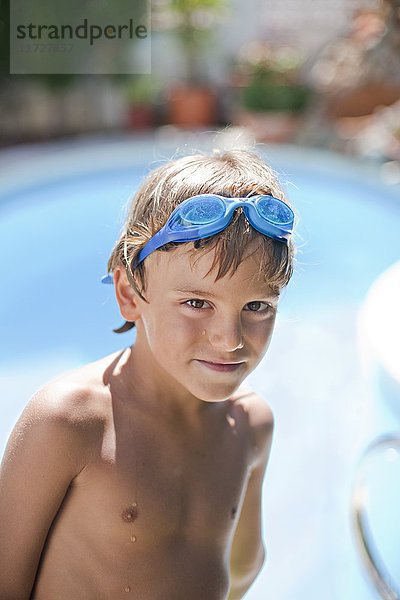 Porträt eines süßen blonden Jungen mit Schwimmbrille im Pool
