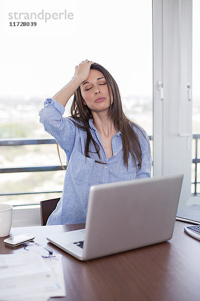 Frau mit Kopfschmerzen vor dem Computer