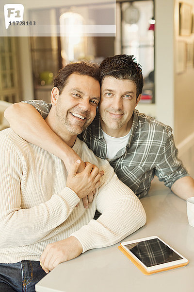 Portrait lächelndes  anhängliches  schwules Paar mit digitaler Tablettenumarmung