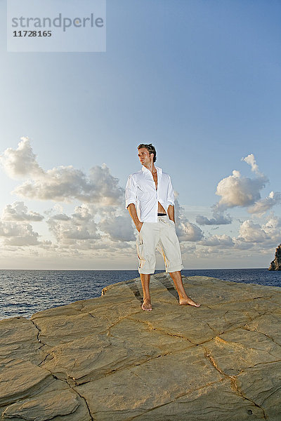 Porträt eines Mannes  der in einer Klippe am Meer steht.