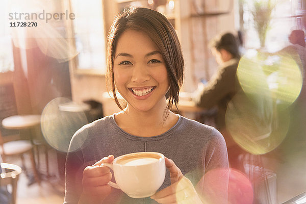Porträt lächelnde Frau trinkt Cappuccino im Café
