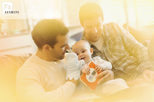 Männliche schwule Eltern mit Puppenspiel mit Baby-Sohn