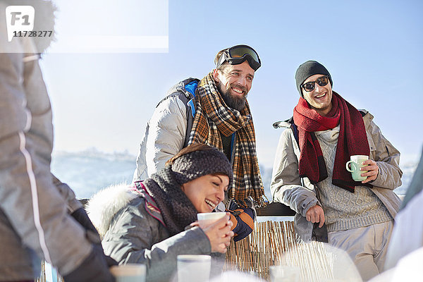 Lächelnde Skifahrerfreunde trinken Kaffee und heißen Kakao außerhalb des Apres-Skis