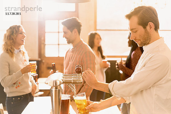 Barkeeper schenkt Bier am Zapfhahn hinter der Bar ein