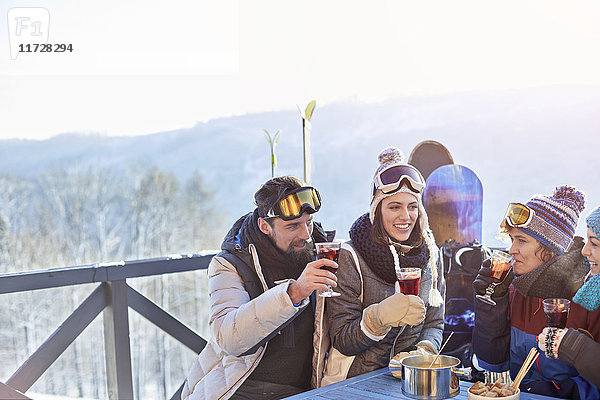 Snowboarder und Skifahrerfreunde trinken Cocktails auf dem Balkon Apres-Ski