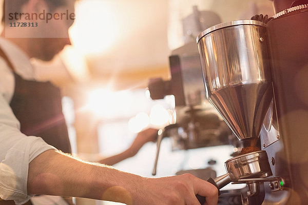 Barista mit Espressomaschine und Mühle im Café