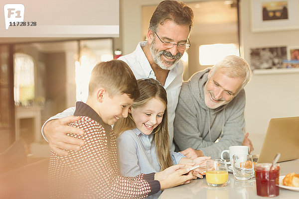 Männliche schwule Eltern und Kinder  die ihr Handy an der Küchenzeile benutzen.