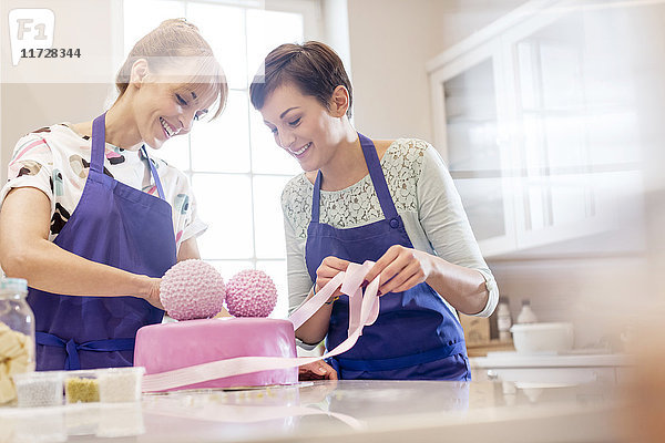 Weibliche Caterer beenden rosa Hochzeitstorte in der Küche