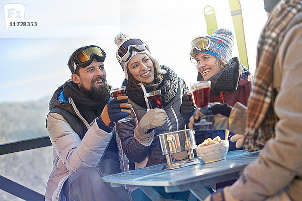 Skifahrerfreunde beim Trinken und Essen am Balkontisch Apres-Ski