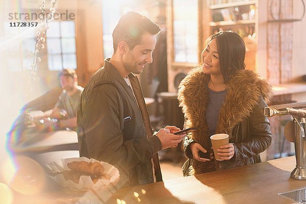 Ehepaar mit Handy und Kaffee an der Theke eines Cafés