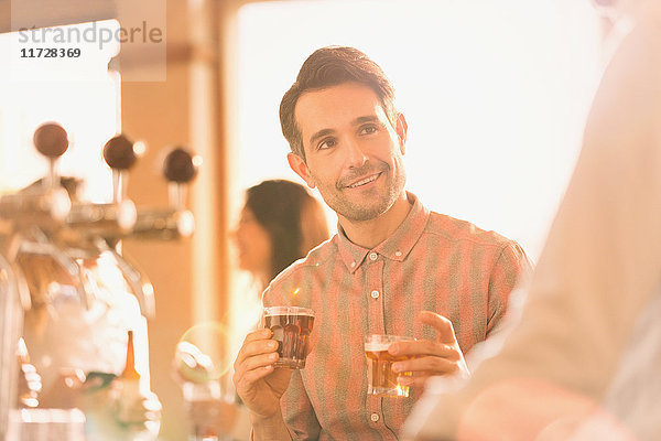 Lächelnder Mann  der an einer Bar Bier probiert