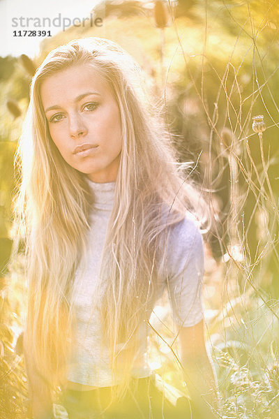 Portrait ernstes  schönes blondes Teenager-Mädchen in sonnigem Feld