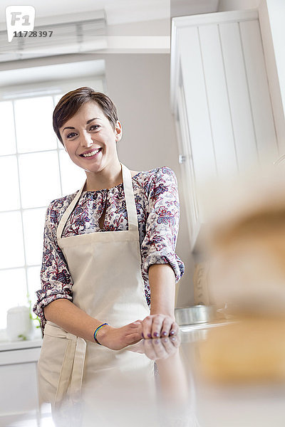 Portrait lächelnde brünette Frau in Schürze in der Küche