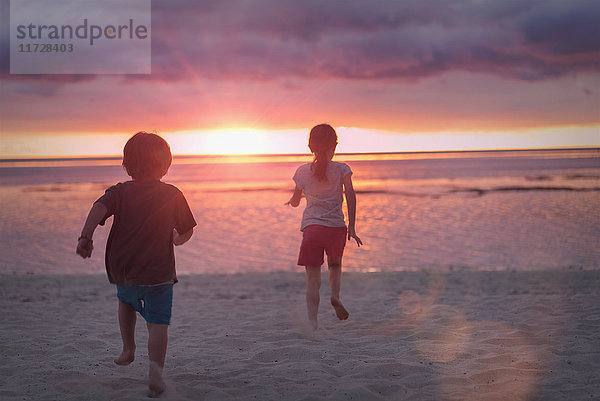 Junge und Mädchen Bruder und Schwester auf ruhigen Sonnenuntergang Strand mit dramatischen Himmel