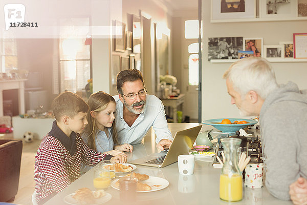 Männliche schwule Eltern und Kinder mit Laptop an der Frühstücksküche