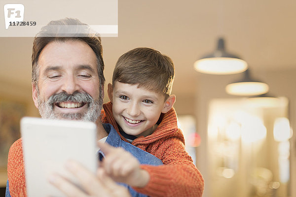 Vater und Sohn verbinden sich und teilen sich ein digitales Tablett.
