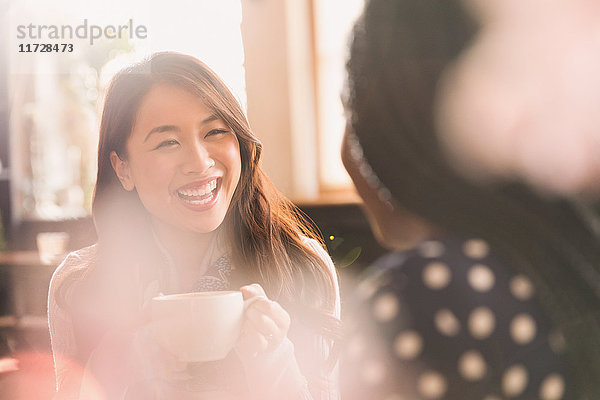 Lachende Frauen im Gespräch und beim Kaffeetrinken in einem Cafe