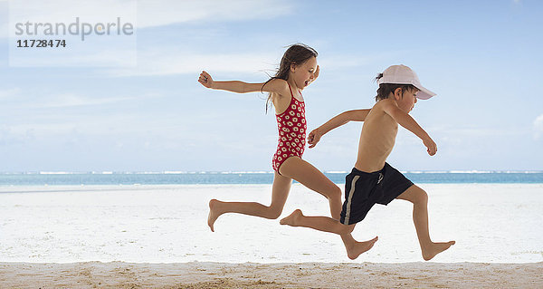 Junge und Mädchen Bruder und Schwester laufen am tropischen Strand