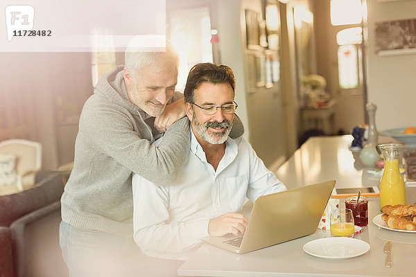 Männliches schwules Paar mit Laptop an der Frühstücksküche