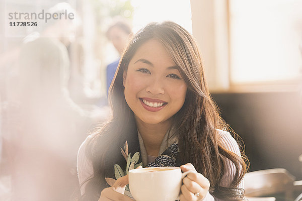 Porträt lächelnde chinesische Frau trinkt Cappuccino im Café