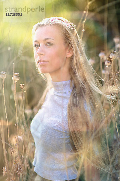 Porträt selbstbewusstes schönes blondes Teenager-Mädchen im hohen Gras