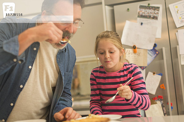 Vater und Tochter essen Kuchen in der Küche